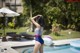 A woman in a bathing suit standing next to a swimming pool.