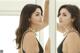 A woman in a black dress looking at herself in the mirror.