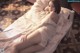 A woman laying on a bed in a white dress.